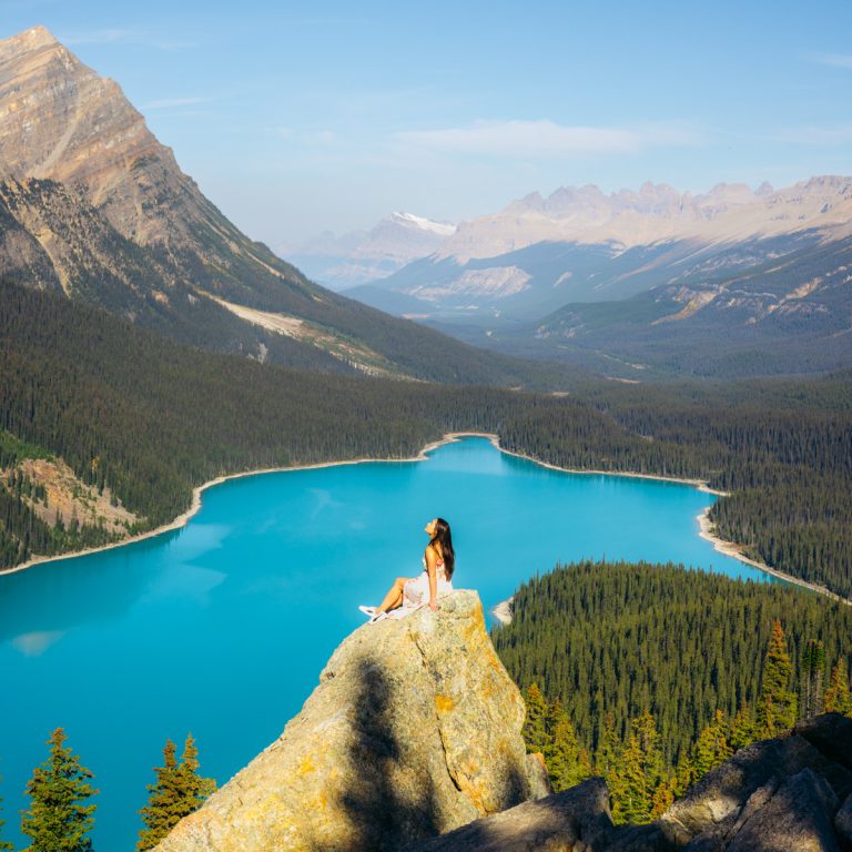 girl sitting on slanted rock at secret viewpoint of Peyto Lake