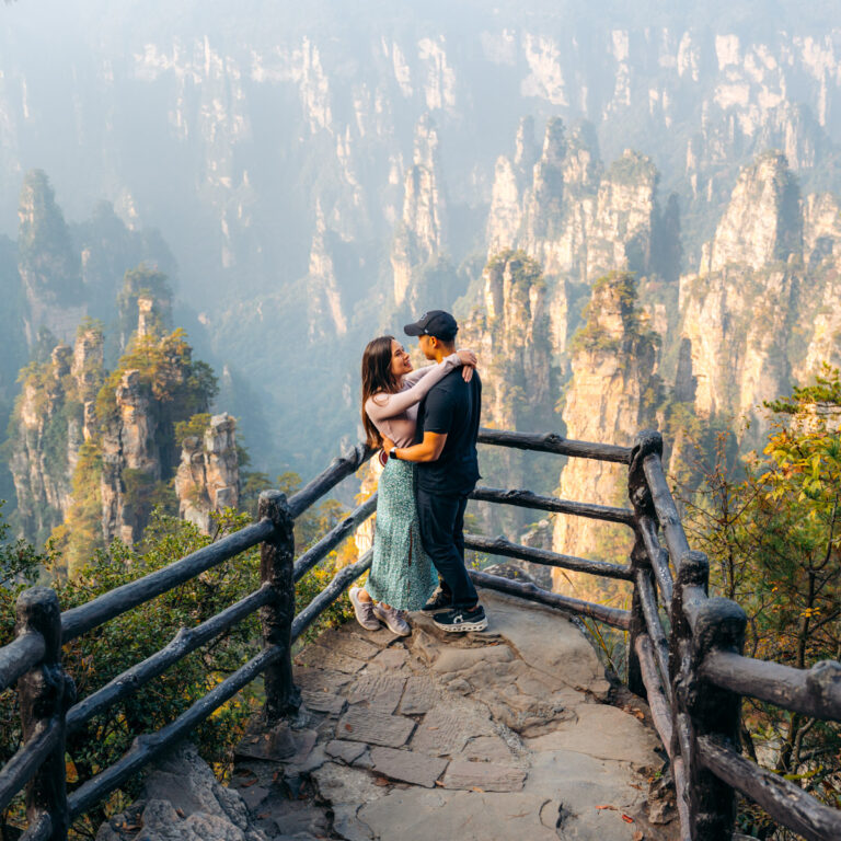 couple standing and hugging at Zhangjiajie lookout during the morning autumn light on Tianzi Mountain