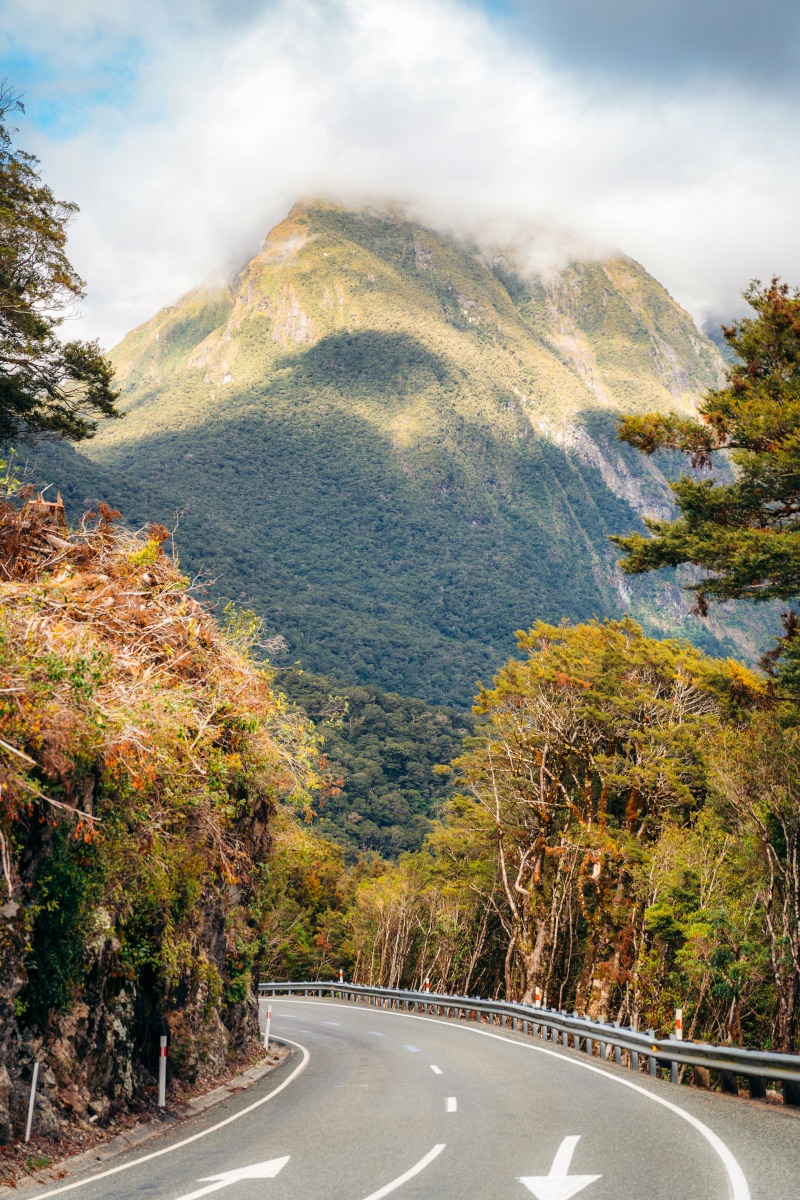 Milford Road shot facing tall mountain with clouds covering the peak in South Island New Zealand